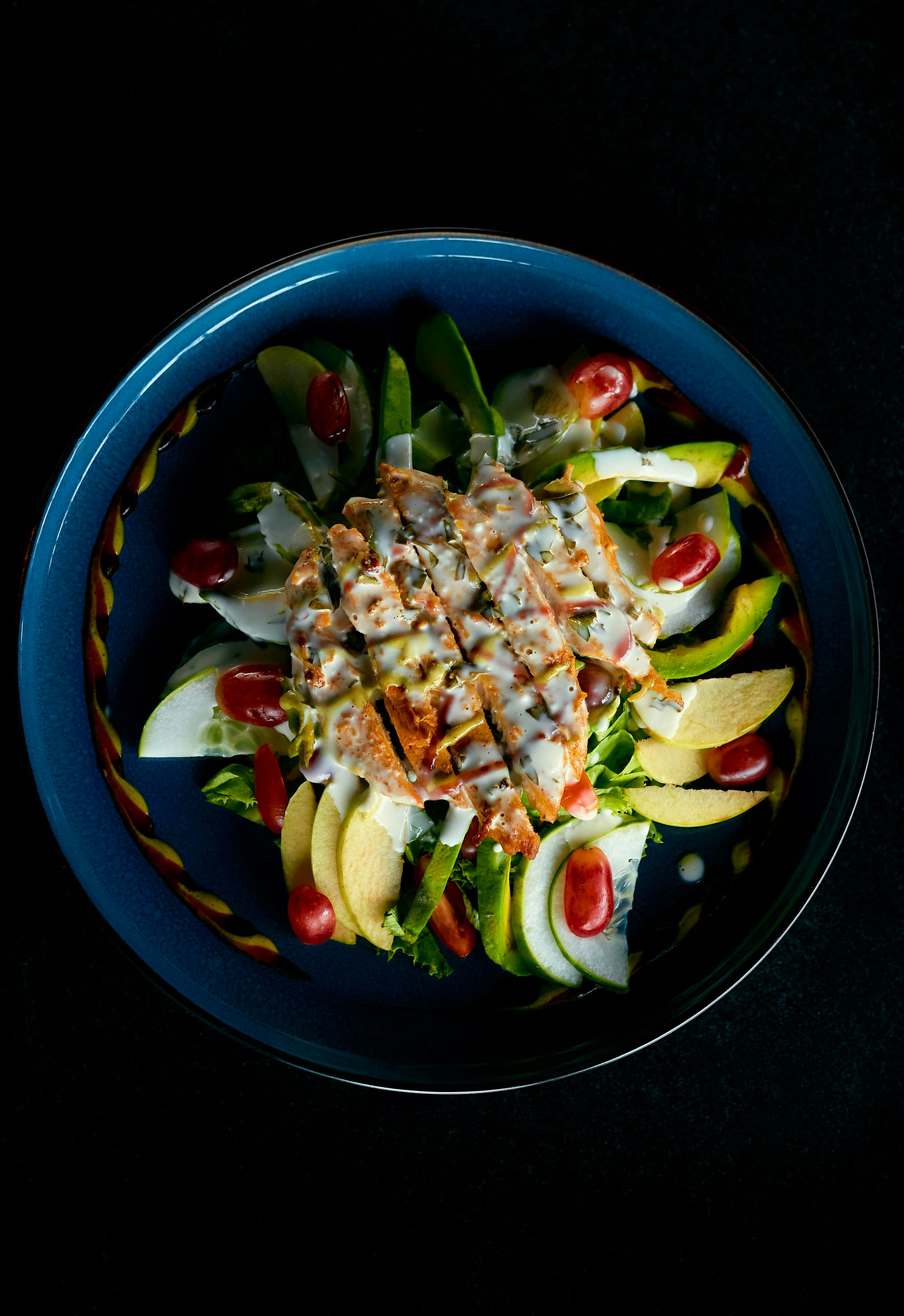 Ensalada de pollo a la plancha con aguacate y tomate sobre fondo oscuro